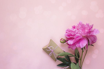 Romantic background with peony and gift box on pink. Copy space.