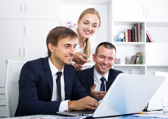 Three cheerful coworkers working in company office