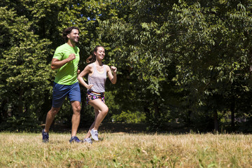 Fototapeta premium Young couple running in the park on a sunny day