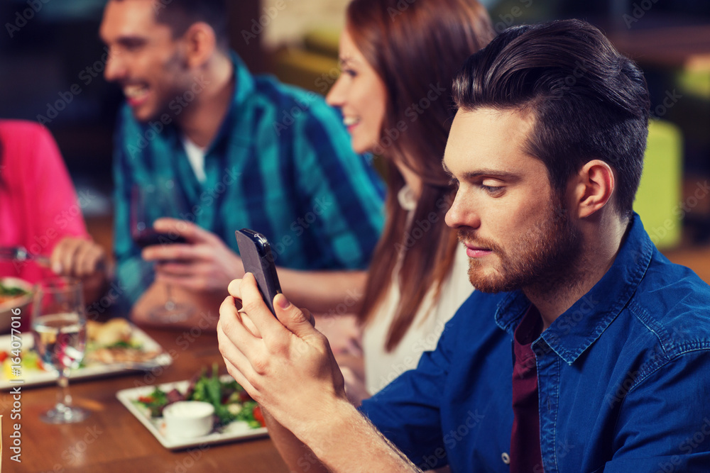 Wall mural man with smartphone and friends at restaurant