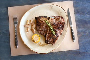 Grilled beefsteak with vegetables and herbs on plate, top view