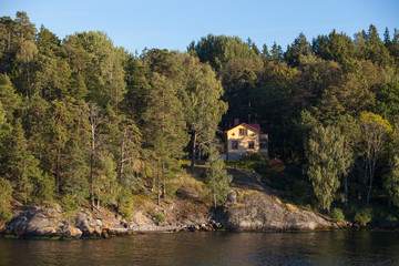 Fototapeta na wymiar View on cottage in forest along Stockholm archipelago, Sweden. Summer sunset time.