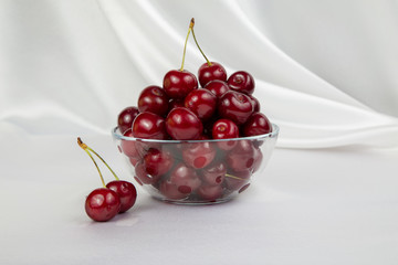 glass vase with big red cherries on a white background