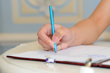 Woman's hand signing a contract. Signed an official document with a pen and paper.