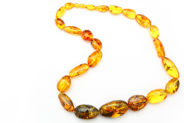 Amber beads made from natural pieces of amber on a white background. Jewelry for women from natural minerals. Petrified resin in the form of beads. Vintage decoration. Top view. Transparent amber