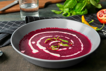 Delicious beet soup with sour cream in bowl on kitchen table