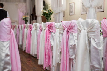 Pink bows on backs of white chairs in the restaurant