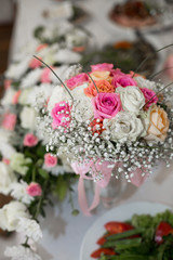 Bouquet of pink and white roses stands on the dinner table