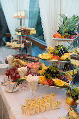 Tired dish with cut fruits stand on table with sweets