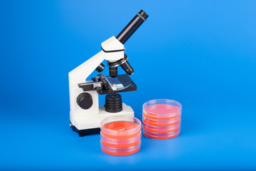 Scientific microscope and petri dishes for scientific research on blue background