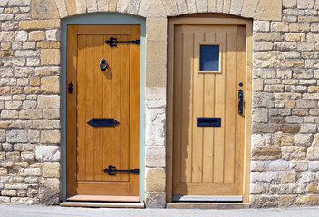 Two light brown wooden doors in an old traditional stone building .