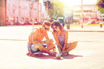 couple with skateboards and smartphone in city