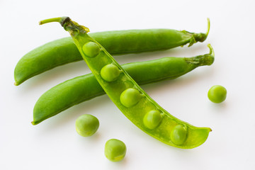 Green peas and pea pod closeup on white. Top view. Food background.