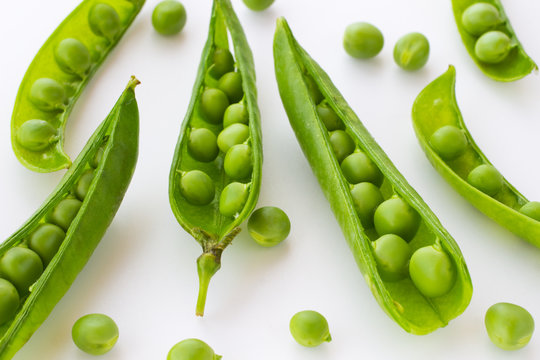 Green peas and pea pod closeup on white. Top view. Food background.