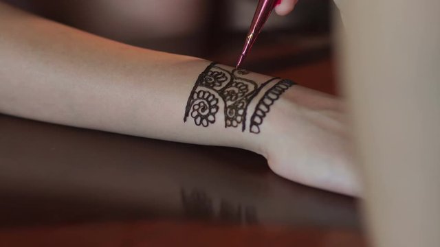 Process of applying mehndi on female's hands. Artist applying henna tattoo on bride's hands. Mehndi is traditional Indian decorative art. 4K