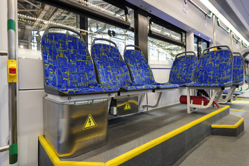 Modern tram inside, city transportation interior with blue seats in row, chrome handles for...