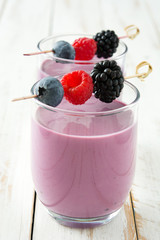 Healthy berry smoothie in glass on white wooden table
