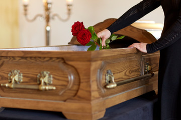 woman with red roses and coffin at funeral