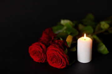Fototapeta na wymiar red roses and burning candle over black background