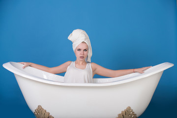 girl with towel turban sitting in white bathtub