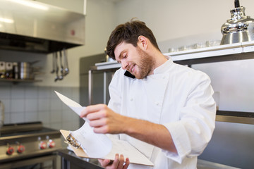 Naklejka na ściany i meble chef cook calling on smartphone at restaurant kitchen