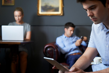 Businesspeople Using Digital Devices In Cafe