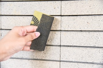 Close-Up View of Hand Rubbing Wall with Sandpaper