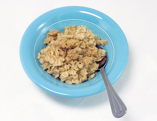 Blue bowl filled with oatmeal and brown sugar with silver spoon. Isolated.