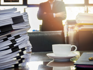 Close up of stack of documents and a cup of coffee on businessman working background
