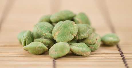 Portion of Wasabi coated Peanuts on wooden background (selective focus)