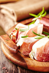 Cured and dried ham with rosemary on a chopping board