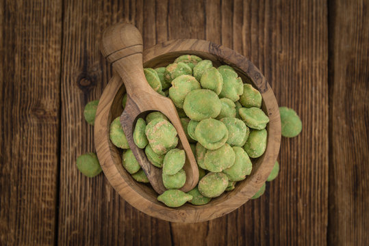 Portion of Wasabi coated Peanuts on wooden background (selective focus)
