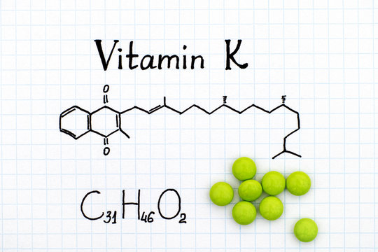 Chemical formula of Vitamin K and pills.