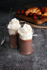 Iced coffee with whipped cream in tall glass and fresh croissant