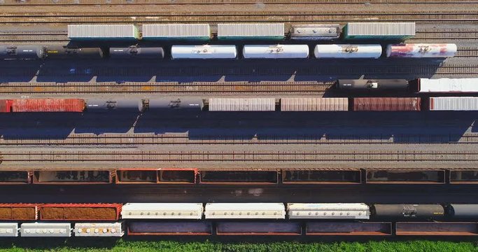 Looking straight down on industrial railroad rail train yard, many trains, tracks. Dynamic aerial view.
