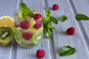 Detox water with kiwi, lemon and raspberries on the grey wooden background