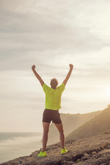 Fototapeta na wymiar Success of a man after jogging / exercising on a clif near the sea / ocean.