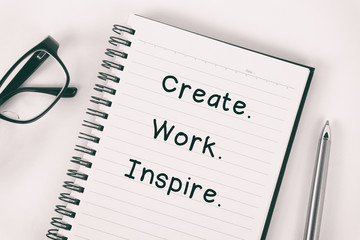 Inspirational quote - Create, work, inspire: written on a note pad with eyeglasses and pen.