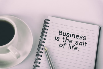 Inspirational quote - Business is the salt of life: written on a note pad with eyeglasses and pen.