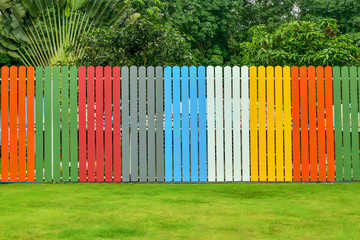 colorful fence with lawns and tree in backyard.