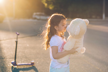 Little beautiful girl playing with a toy bear