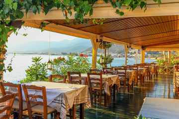 empty wooden terrace of a restaurant or cafe on the shores of a warm summer sea on an early sunny morning