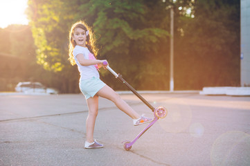 Little beautiful girl is riding a scooter