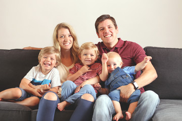 Young family with three boys lifestyle at home on the couch playing together