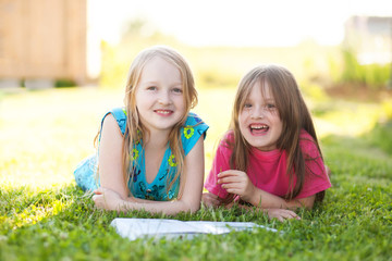 Two shooler sisters reading outdoors, having fun