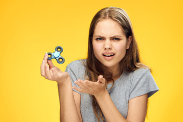 Beautiful young woman on a yellow background holds a spinner