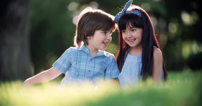 two small children,Caucasian boy and Asian girl having fun in the Park ,slow motion