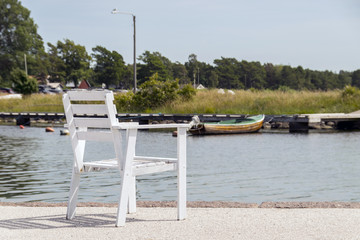 Fototapeta premium En tom vit stol på kajen