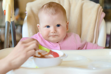 A cheerful happy child eats porridge.