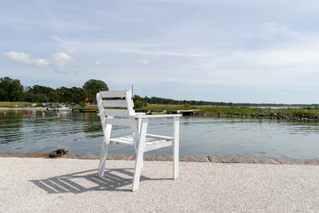 En tom vit stol på kajen